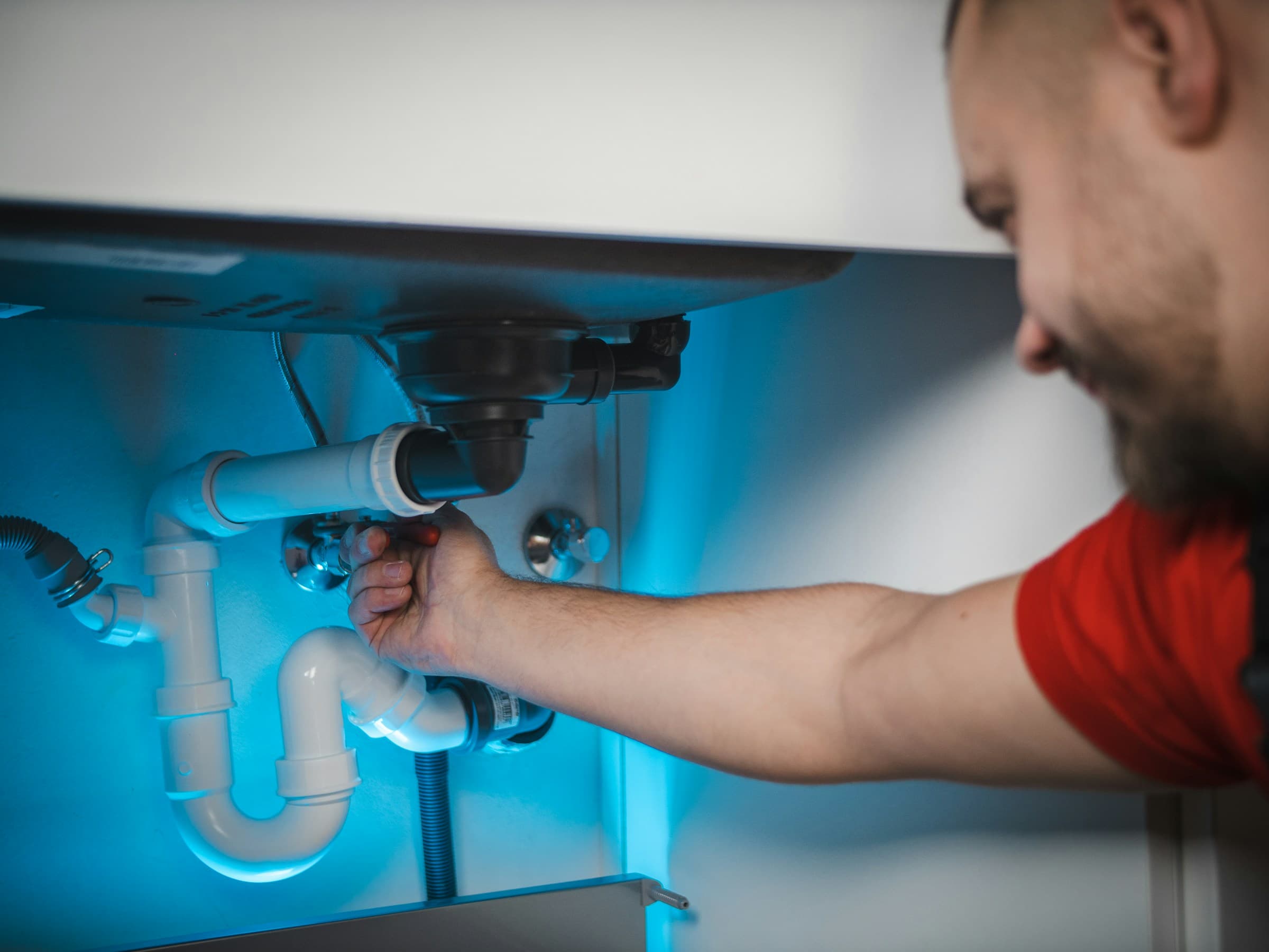 Monteur bei der Installation eines Siphons unter einem Waschbecken
